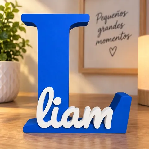 Letra L azul impresa en 3D con el nombre Liam en blanco, apoyada sobre un mueble