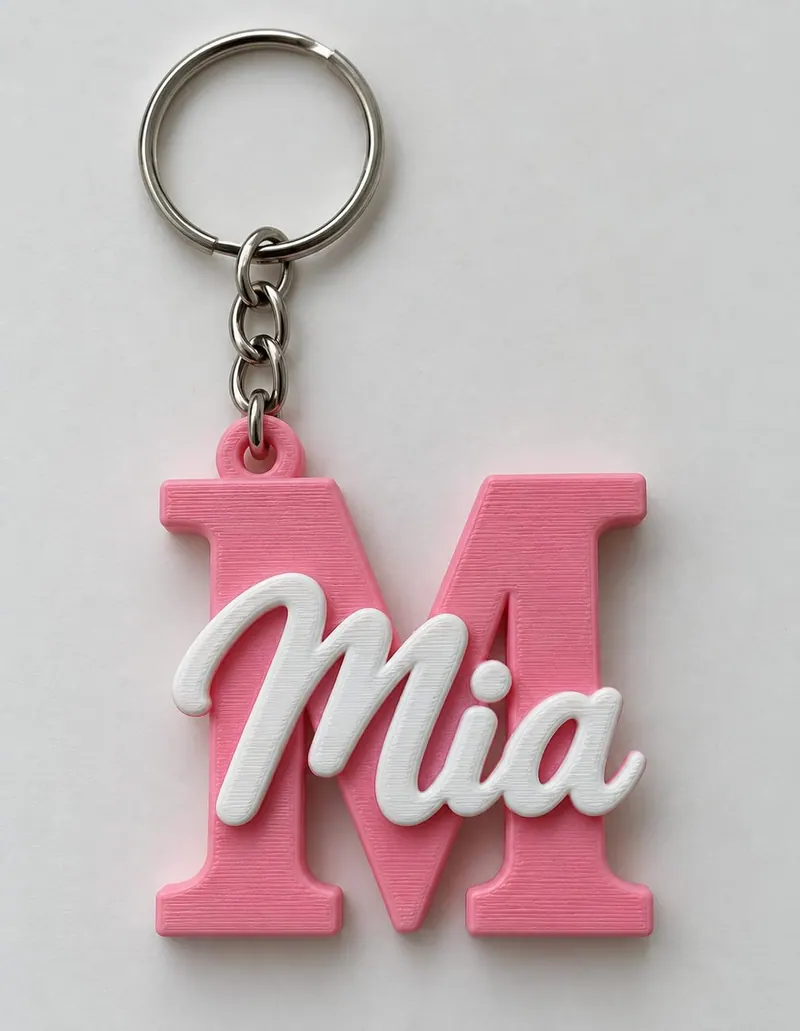 Llavero impreso en 3D con la letra M en rosa y el nombre Mia en blanco, con argolla metálica
