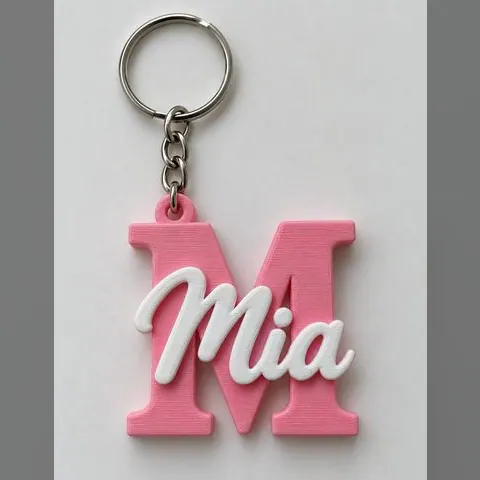 Llavero impreso en 3D con la letra M en rosa y el nombre Mia en blanco, con argolla metálica